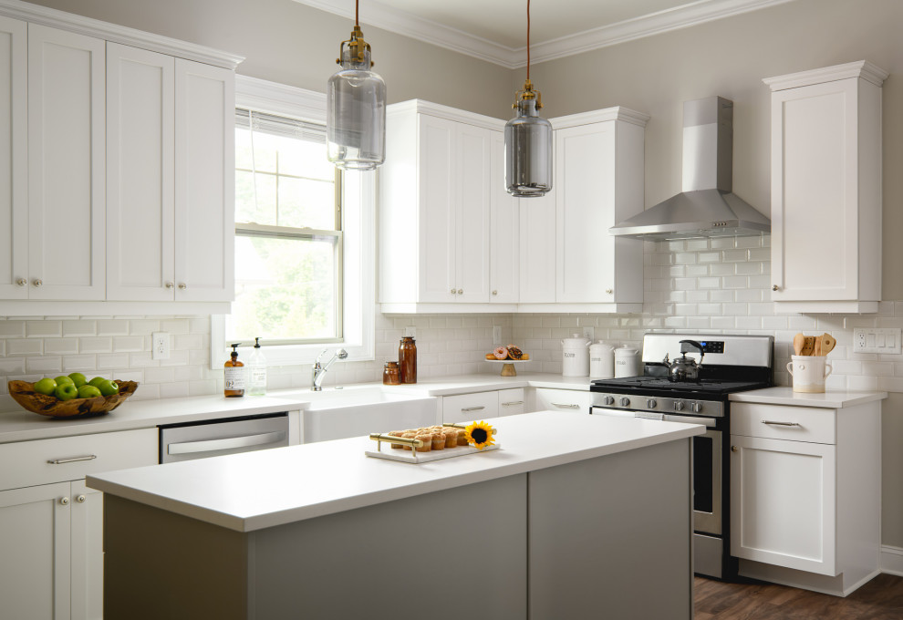 Kitchen - transitional l-shaped dark wood floor and brown floor kitchen idea with a farmhouse sink, shaker cabinets, white cabinets, white backsplash, subway tile backsplash, stainless steel appliances, an island and white countertops