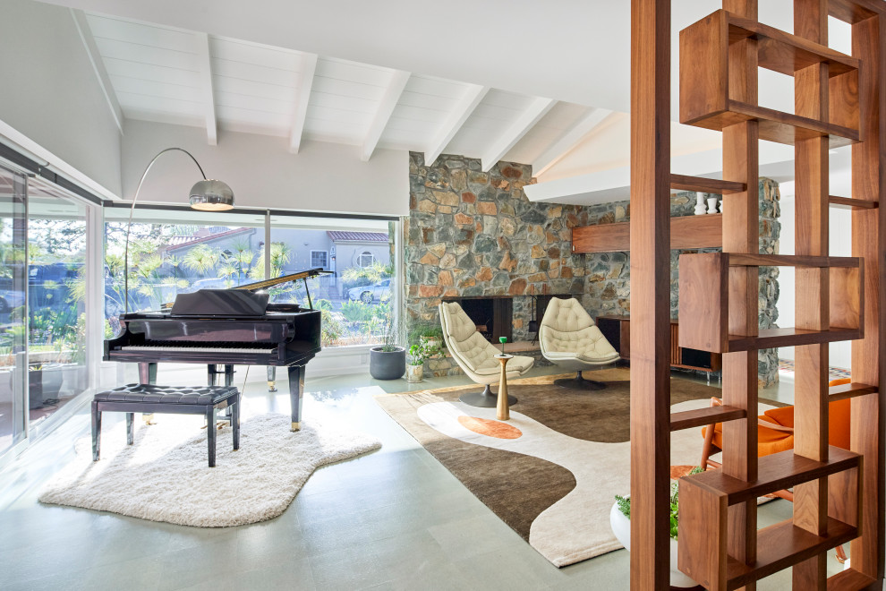 This is an example of a mid-sized midcentury open concept living room in San Diego with a music area, white walls, cork floors, a standard fireplace, a stone fireplace surround, grey floor and exposed beam.