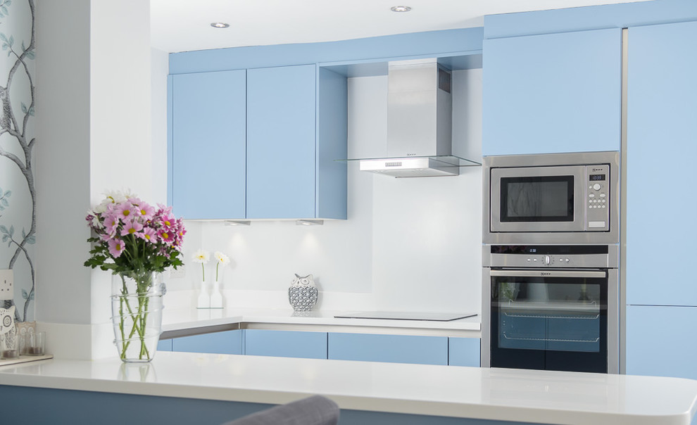 Mid-sized modern l-shaped eat-in kitchen in Other with flat-panel cabinets, blue cabinets, solid surface benchtops, white splashback, panelled appliances, linoleum floors and no island.