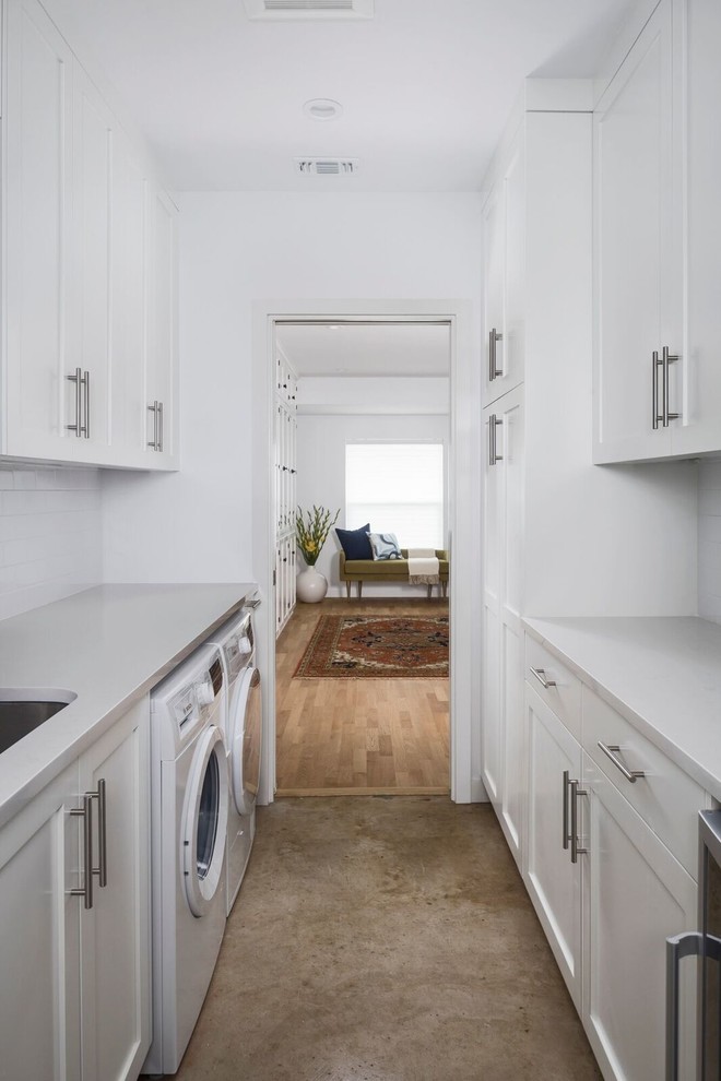 Mid-sized midcentury galley dedicated laundry room in Austin with an undermount sink, shaker cabinets, white cabinets, quartz benchtops, white walls, concrete floors and a side-by-side washer and dryer.