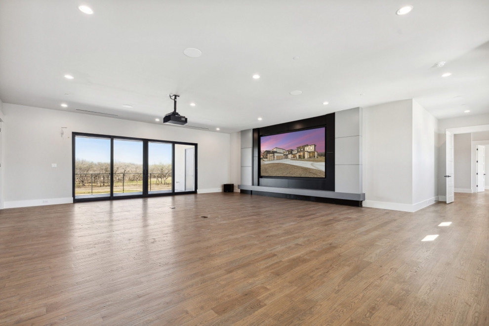 Modelo de cine en casa abierto minimalista extra grande con paredes grises, suelo de madera en tonos medios, pantalla de proyección y suelo beige