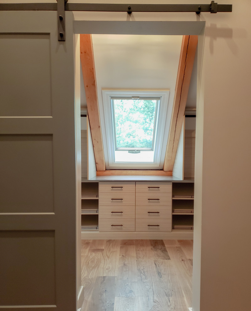 This is an example of a mid-sized walk-in wardrobe in Burlington with flat-panel cabinets and light wood cabinets.
