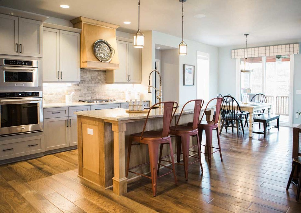 Inspiration for a mid-sized transitional kitchen remodel with a farmhouse sink, granite countertops, gray backsplash, stainless steel appliances and an island