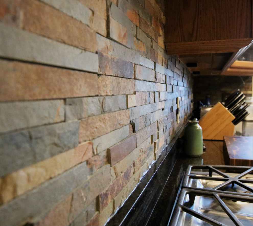 Eat-in kitchen - mid-sized rustic l-shaped eat-in kitchen idea with glass-front cabinets, light wood cabinets, granite countertops, multicolored backsplash, stone tile backsplash, stainless steel appliances, an island and black countertops
