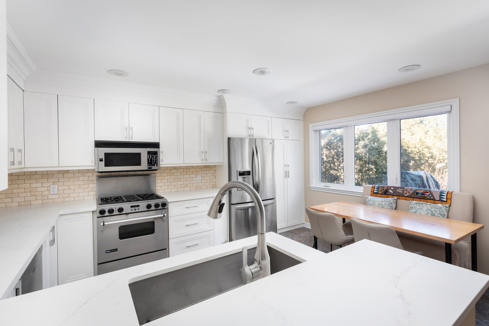 Photo of a large modern l-shaped open plan kitchen in Toronto with an undermount sink, shaker cabinets, white cabinets, quartz benchtops, beige splashback, ceramic splashback, stainless steel appliances, porcelain floors, a peninsula, beige floor and white benchtop.