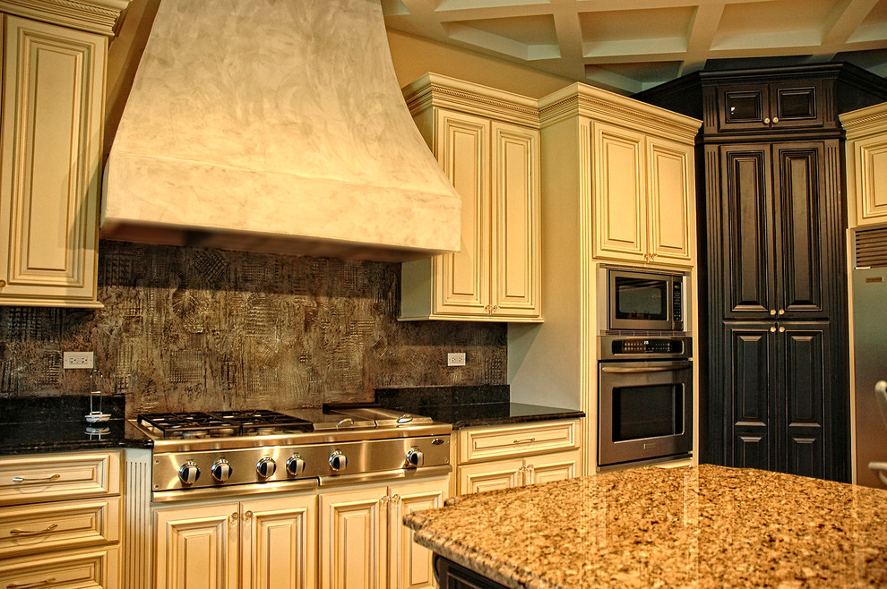 Large elegant l-shaped kitchen pantry photo in Phoenix with an undermount sink, raised-panel cabinets, white cabinets, granite countertops, multicolored backsplash, stainless steel appliances and an island