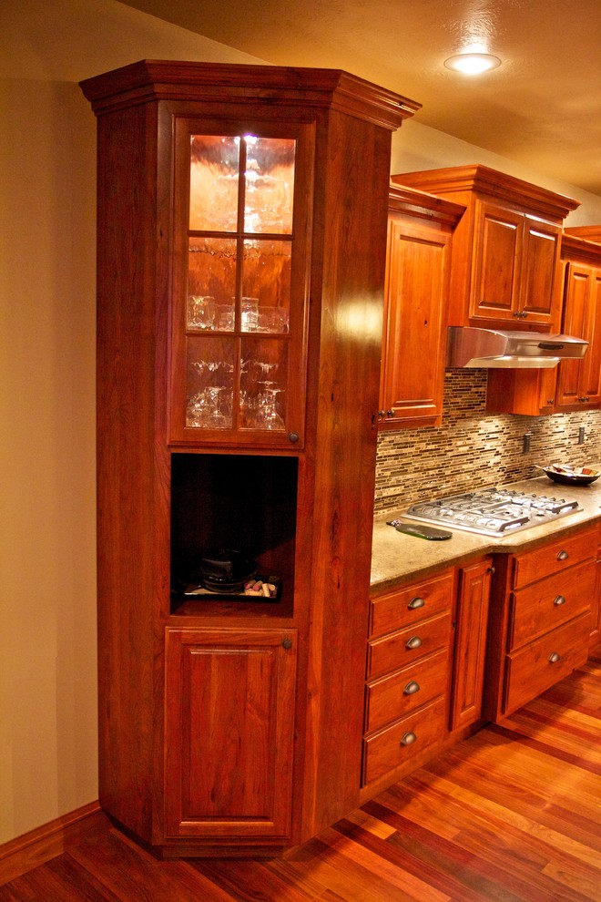 Open concept kitchen - large l-shaped medium tone wood floor open concept kitchen idea with an undermount sink, raised-panel cabinets, dark wood cabinets, multicolored backsplash, glass tile backsplash, stainless steel appliances and an island