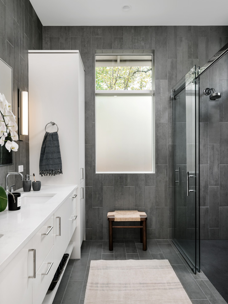 Contemporary bathroom in Austin with flat-panel cabinets, white cabinets, a curbless shower, gray tile, an undermount sink, grey floor, a sliding shower screen, white benchtops and a double vanity.