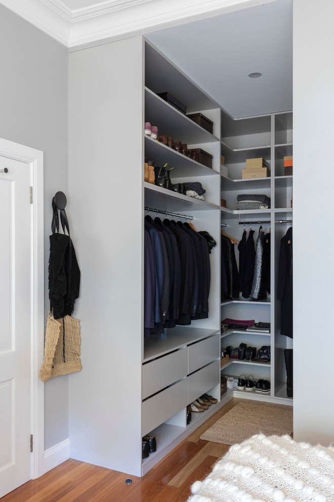 Mid-sized traditional gender-neutral walk-in wardrobe in Sydney with open cabinets, blue cabinets and medium hardwood floors.