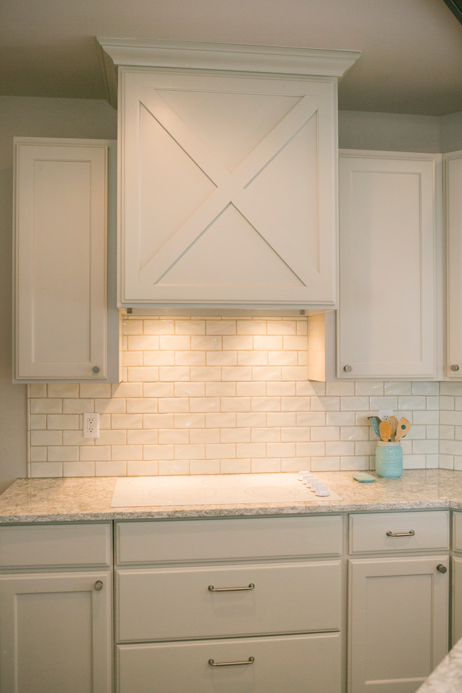 Open concept kitchen - mid-sized rustic l-shaped open concept kitchen idea with raised-panel cabinets, white cabinets, granite countertops, white backsplash, subway tile backsplash, stainless steel appliances, an island and gray countertops