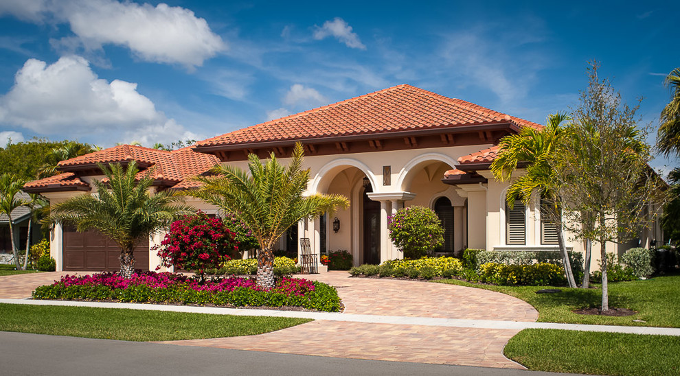 Mid-sized mediterranean one-storey stucco beige house exterior in Miami with a tile roof and a hip roof.