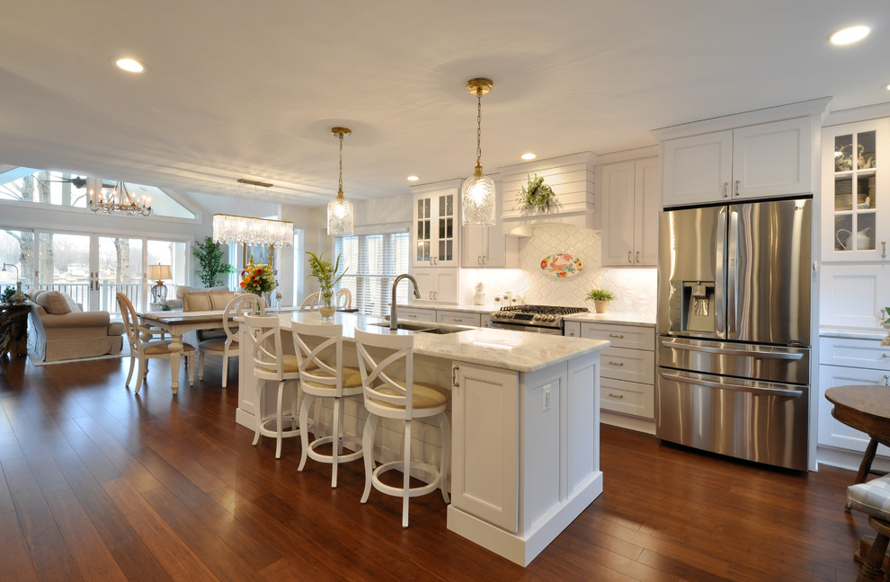 Photo of a large beach style u-shaped eat-in kitchen in DC Metro with an undermount sink, recessed-panel cabinets, white cabinets, stainless steel appliances, dark hardwood floors and with island.