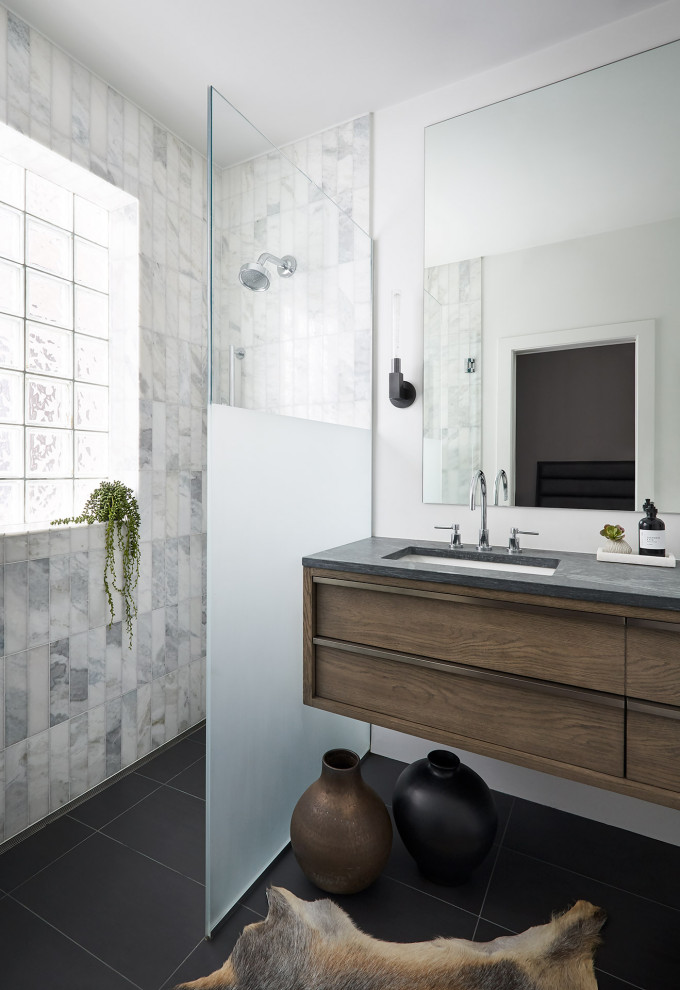 This is an example of a mid-sized contemporary master bathroom in Chicago with flat-panel cabinets, medium wood cabinets, a curbless shower, white tile, marble, white walls, slate floors, an undermount sink, limestone benchtops, black floor, a hinged shower door and grey benchtops.