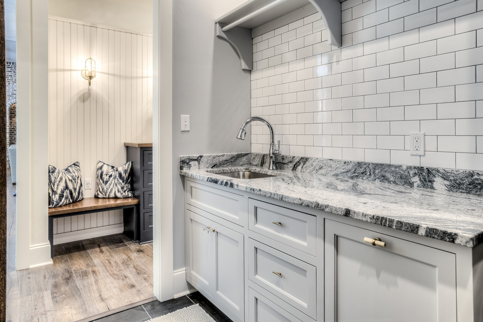 Photo of a mid-sized country galley laundry room in Atlanta with an undermount sink, grey cabinets, granite benchtops, grey walls, a side-by-side washer and dryer and recessed-panel cabinets.