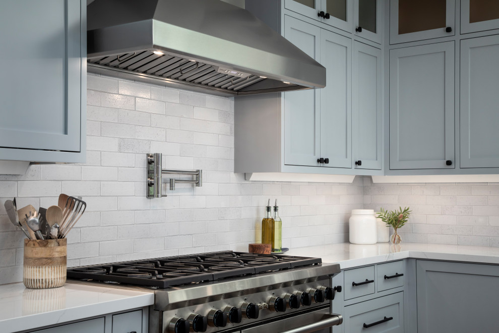 Eat-in kitchen - large transitional u-shaped medium tone wood floor and brown floor eat-in kitchen idea in San Francisco with a farmhouse sink, shaker cabinets, medium tone wood cabinets, quartz countertops, white backsplash, brick backsplash, stainless steel appliances, two islands and white countertops