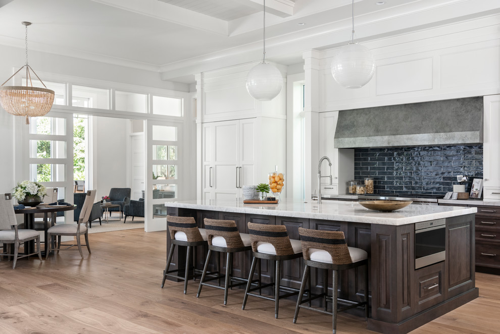 Inspiration for a huge timeless galley medium tone wood floor and brown floor eat-in kitchen remodel in Miami with raised-panel cabinets, dark wood cabinets, green backsplash, stainless steel appliances, an island and white countertops