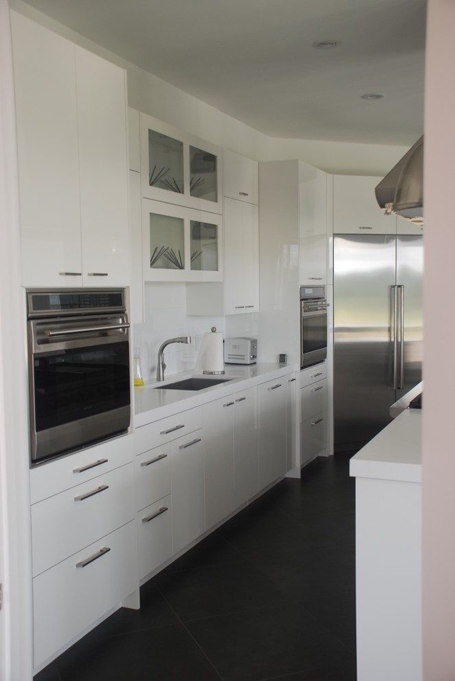 Large contemporary galley eat-in kitchen in Louisville with an undermount sink, flat-panel cabinets, white cabinets, quartz benchtops, white splashback, porcelain splashback, stainless steel appliances and with island.