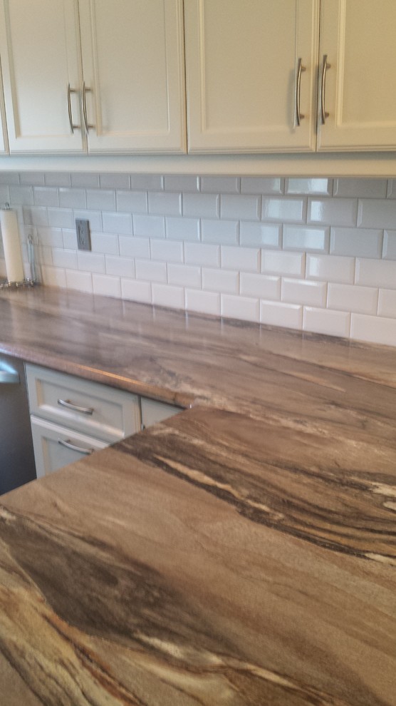 Kitchen - mid-sized traditional kitchen idea with a double-bowl sink, raised-panel cabinets, white cabinets, white backsplash, glass tile backsplash, stainless steel appliances and a peninsula