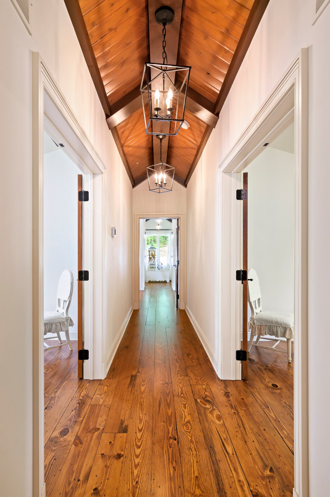 Design ideas for a large mediterranean hallway in Kansas City with white walls, medium hardwood floors and brown floor.