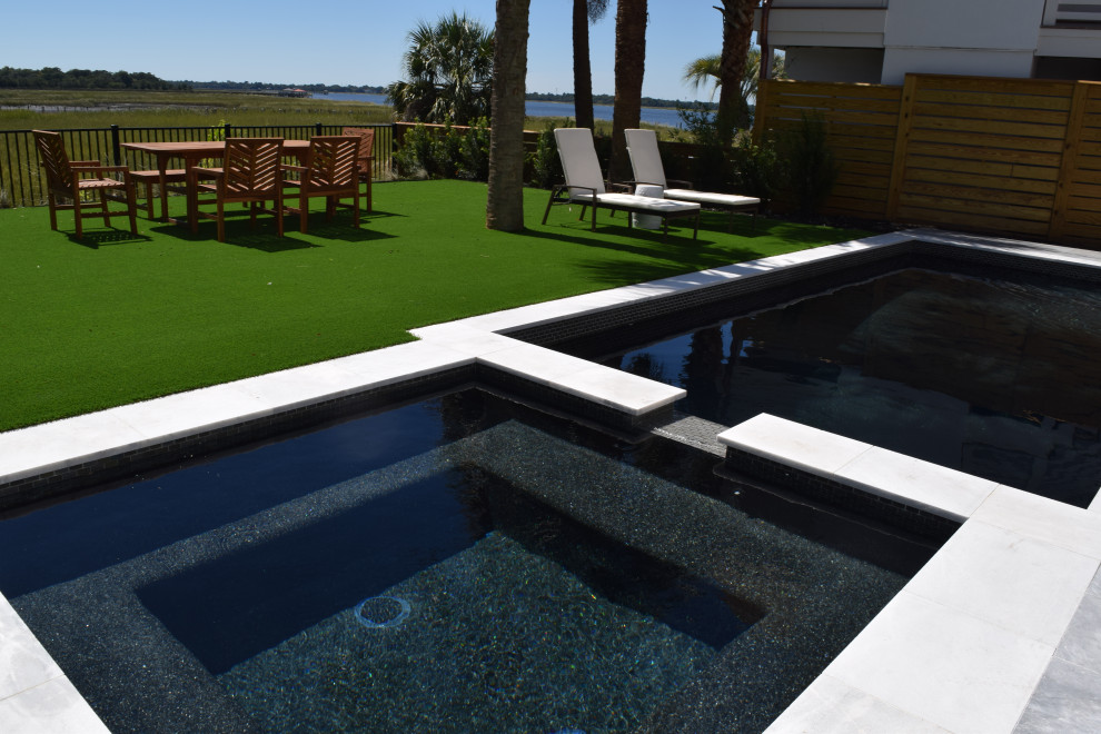 Bild på en liten funkis pool på baksidan av huset, med naturstensplattor