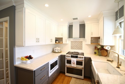 Bright U-shaped kitchen with white shaker RTA cabinets, gray base cabinets, subway backsplash, farmhouse sink, and stainless range.