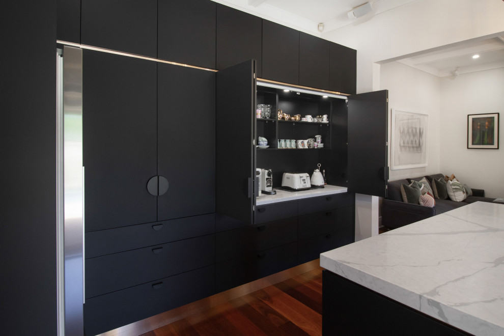 Inspiration för stora moderna vitt kök, med en undermonterad diskho, luckor med infälld panel, svarta skåp, bänkskiva i kvarts, stänkskydd med metallisk yta, svarta vitvaror, mellanmörkt trägolv och en köksö