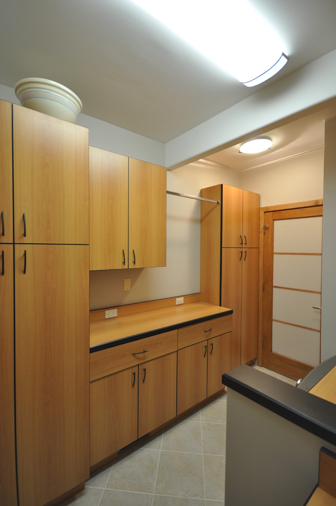 This is an example of a large traditional galley dedicated laundry room in Philadelphia with flat-panel cabinets, wood benchtops, beige walls, ceramic floors, a side-by-side washer and dryer and medium wood cabinets.
