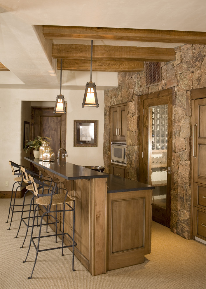 This is an example of a country galley seated home bar in Denver with carpet, recessed-panel cabinets and dark wood cabinets.