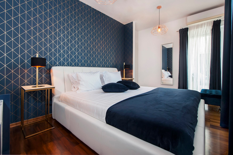 Esempio di una camera matrimoniale minimal di medie dimensioni con pareti blu, pavimento in legno verniciato, pavimento marrone e carta da parati
