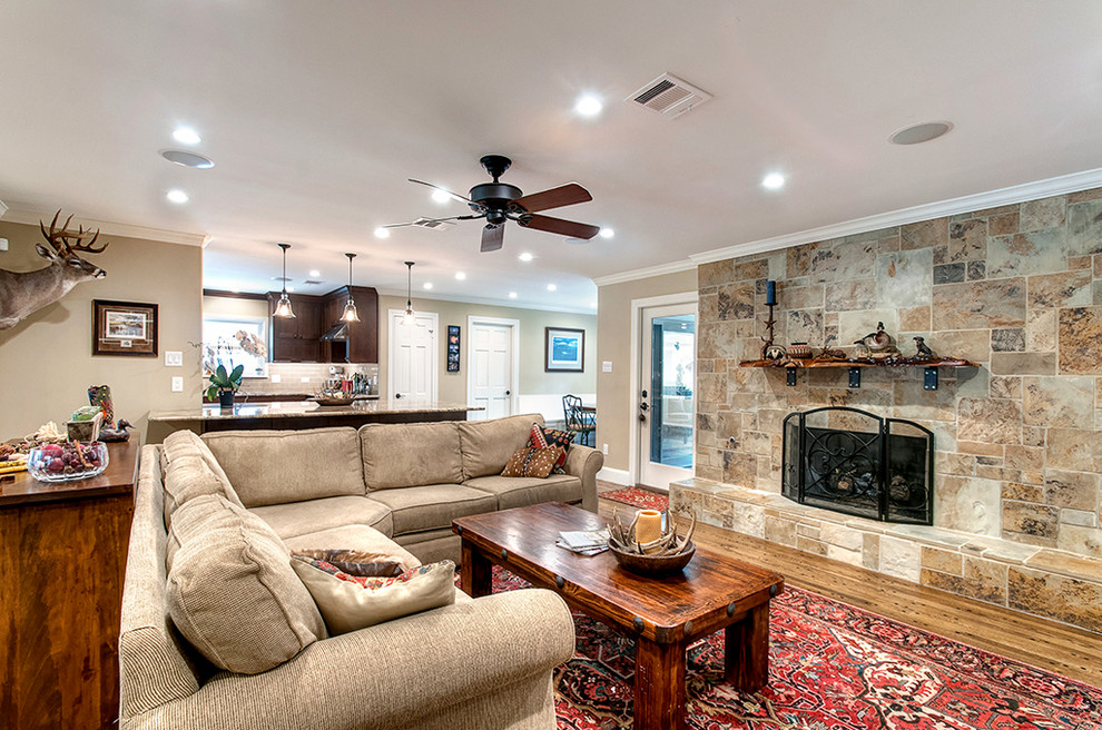 Photo of a large traditional open concept living room in Houston with beige walls, medium hardwood floors, a standard fireplace, a stone fireplace surround, no tv and brown floor.
