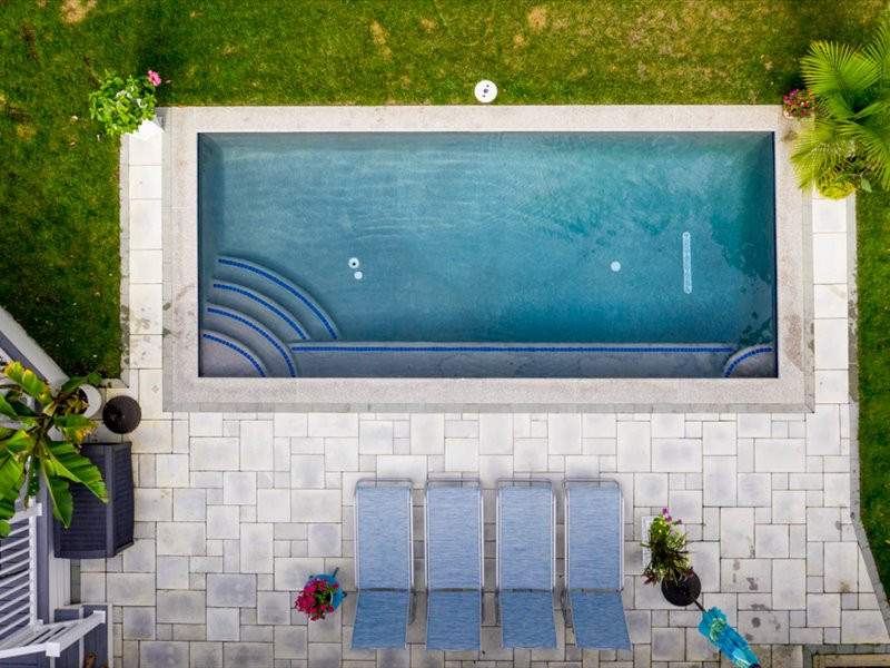 Diseño de piscina clásica renovada pequeña rectangular en patio trasero con adoquines de hormigón