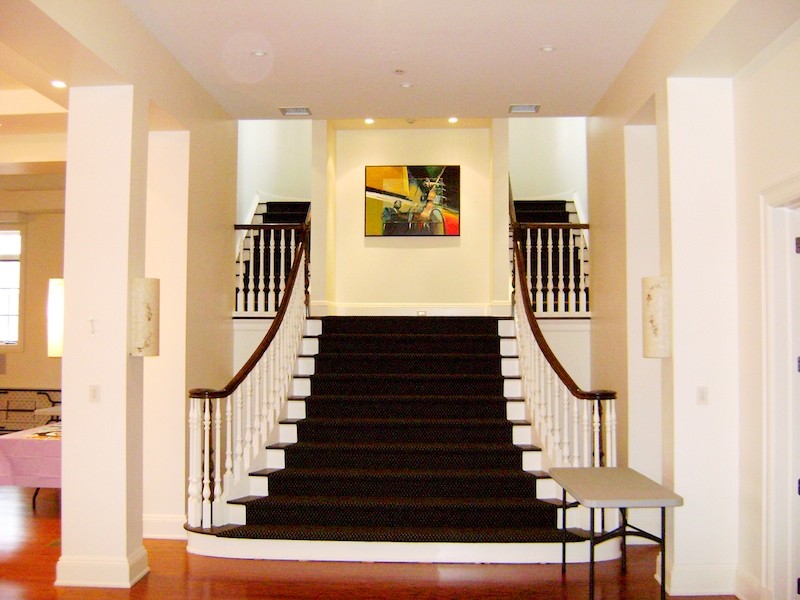 Photo of a large traditional carpeted straight staircase in New York with painted wood risers.