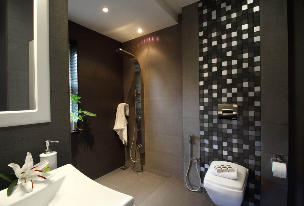 Contemporary bathroom in Bengaluru with a wall-mount toilet, a curbless shower, gray tile, stone tile, grey walls and concrete floors.