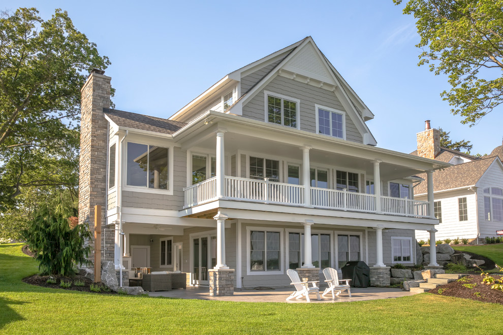 This is an example of a large beach style three-storey beige exterior in Grand Rapids with vinyl siding and a gable roof.