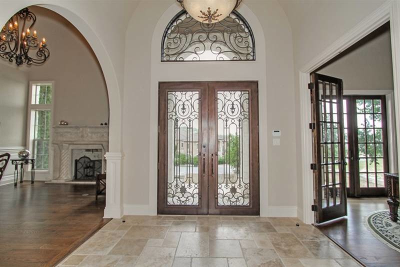 This is an example of a mid-sized traditional foyer in Austin with beige walls, travertine floors, a double front door and a dark wood front door.