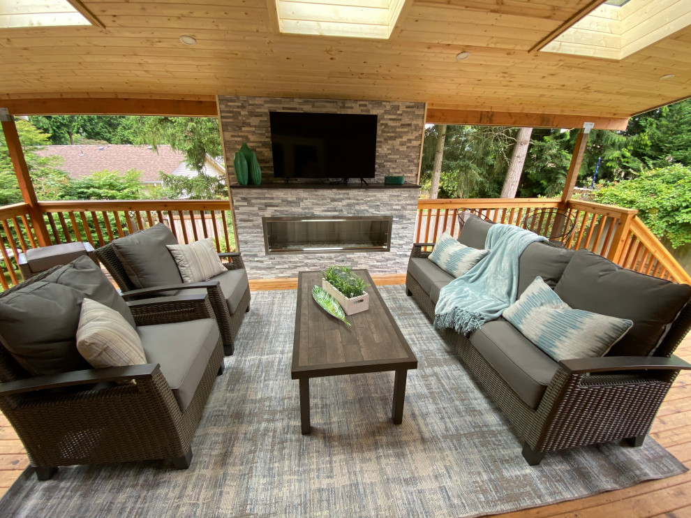 Design ideas for a large transitional backyard deck with with fireplace, a roof extension and wood railing.