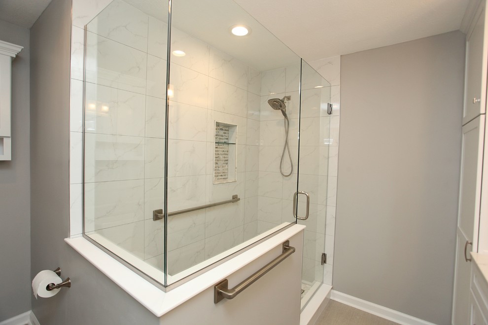 Transitional bathroom in Indianapolis with recessed-panel cabinets, white cabinets, a drop-in tub, a corner shower, white tile, ceramic tile, beige walls, concrete floors, a drop-in sink, engineered quartz benchtops, black floor, a hinged shower door and multi-coloured benchtops.
