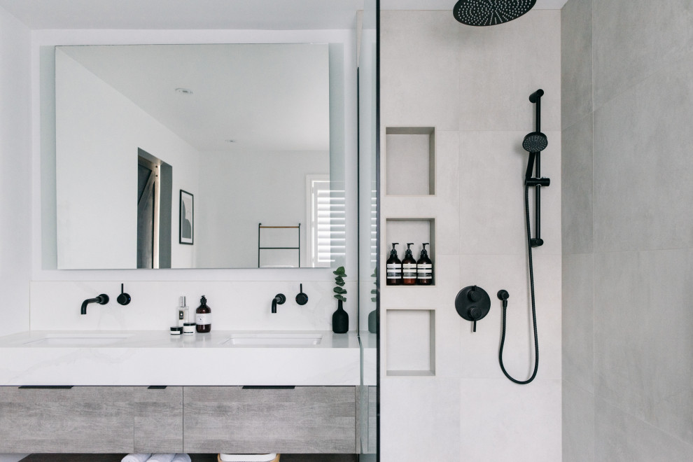 This is an example of a mid-sized scandinavian master bathroom in Toronto with flat-panel cabinets, light wood cabinets, a freestanding tub, a curbless shower, a one-piece toilet, gray tile, porcelain tile, white walls, porcelain floors, an undermount sink, quartzite benchtops, grey floor, an open shower, white benchtops, a niche, a double vanity and a floating vanity.