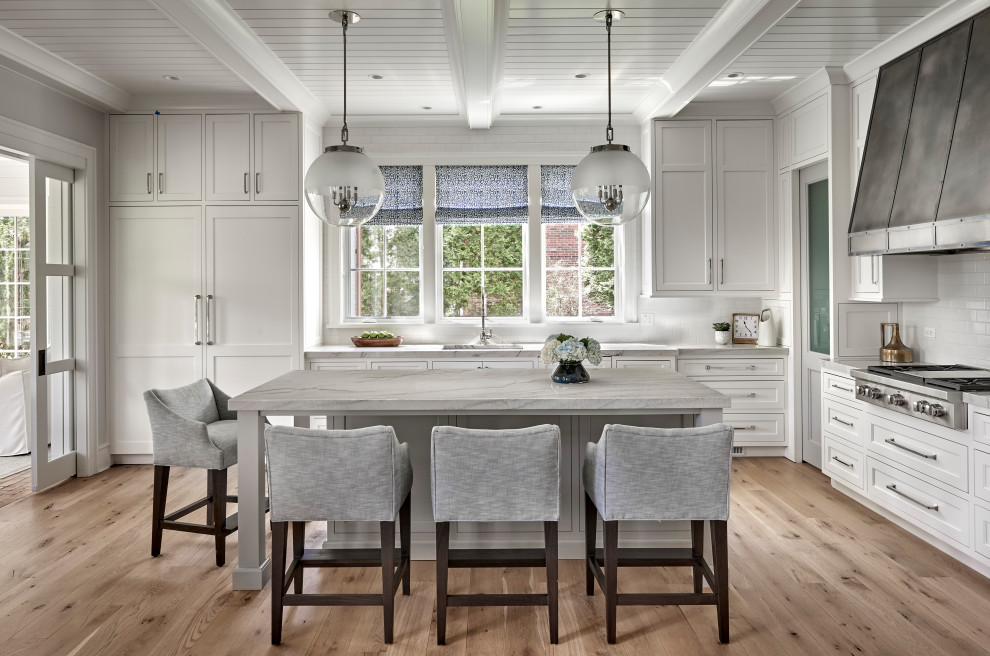 Inspiration for a light wood floor and coffered ceiling kitchen remodel in Chicago with an undermount sink, shaker cabinets, white cabinets, marble countertops, white backsplash, subway tile backsplash, stainless steel appliances, an island and white countertops