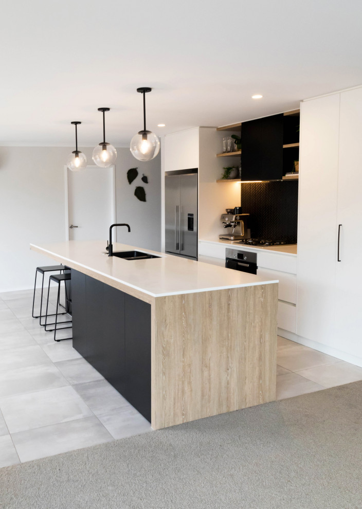This is an example of a mid-sized scandinavian galley eat-in kitchen in Auckland with a double-bowl sink, flat-panel cabinets, black cabinets, solid surface benchtops, black splashback, mosaic tile splashback, stainless steel appliances, porcelain floors, with island, grey floor and white benchtop.