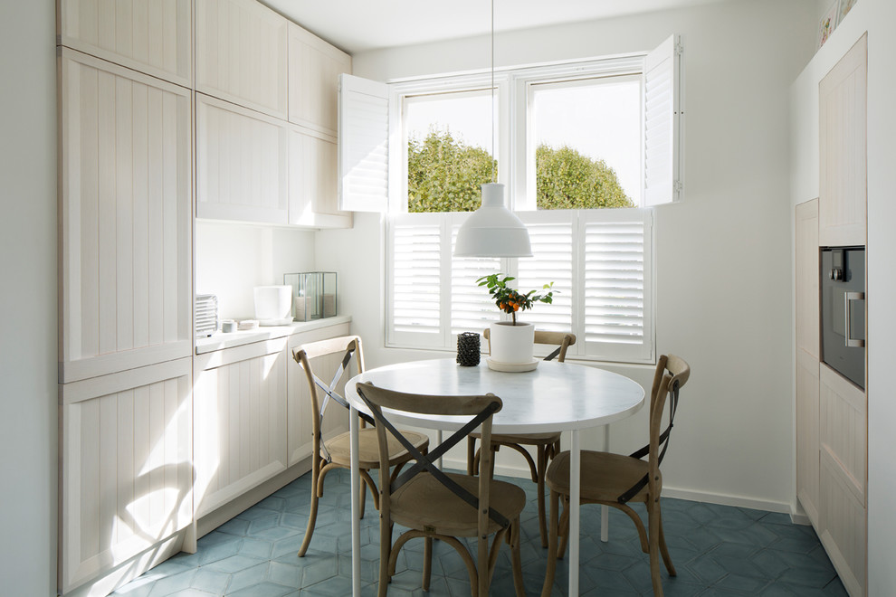 Mid-sized contemporary galley eat-in kitchen in London with a drop-in sink, beaded inset cabinets, light wood cabinets, concrete benchtops, white splashback, cement tile splashback, stainless steel appliances, cement tiles, no island and blue floor.