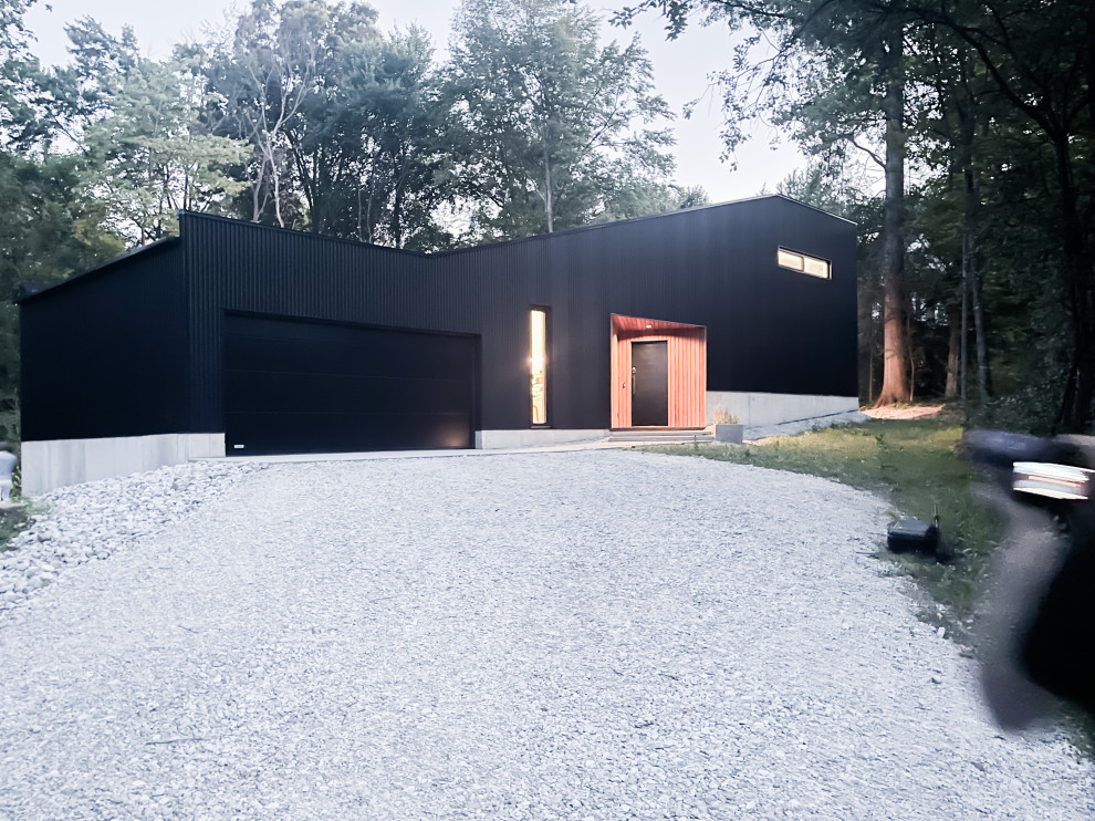 Пример оригинального дизайна: маленький, двухэтажный, черный дом в современном стиле с облицовкой из металла и плоской крышей для на участке и в саду