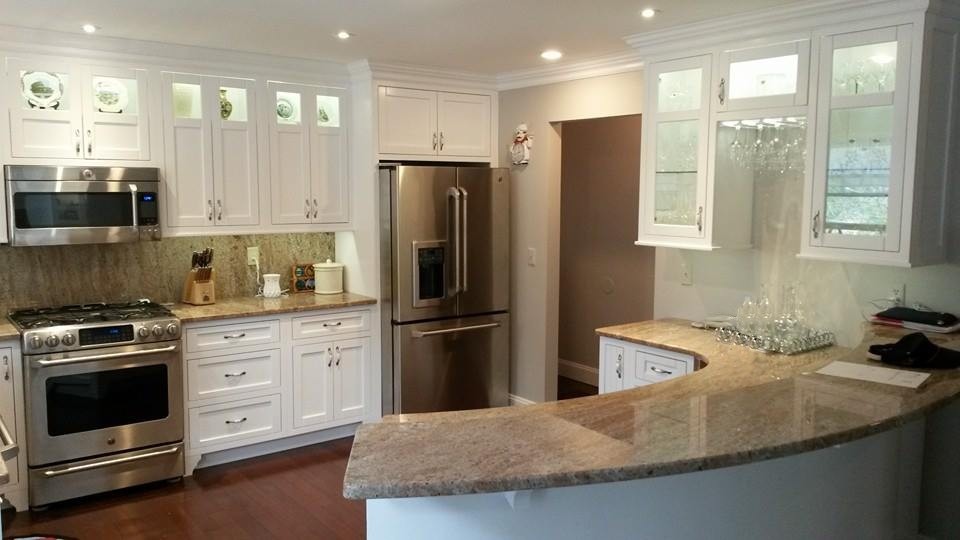 Eat-in kitchen - mid-sized transitional u-shaped medium tone wood floor and brown floor eat-in kitchen idea with shaker cabinets, white cabinets, granite countertops, brown backsplash, stone slab backsplash, white appliances, a peninsula and a farmhouse sink