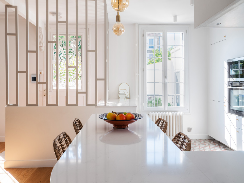 Große Moderne Wohnküche in U-Form mit weißen Schränken, Laminat-Arbeitsplatte, Küchenrückwand in Weiß, Rückwand aus Porzellanfliesen, Elektrogeräten mit Frontblende, Keramikboden, buntem Boden und weißer Arbeitsplatte in Paris