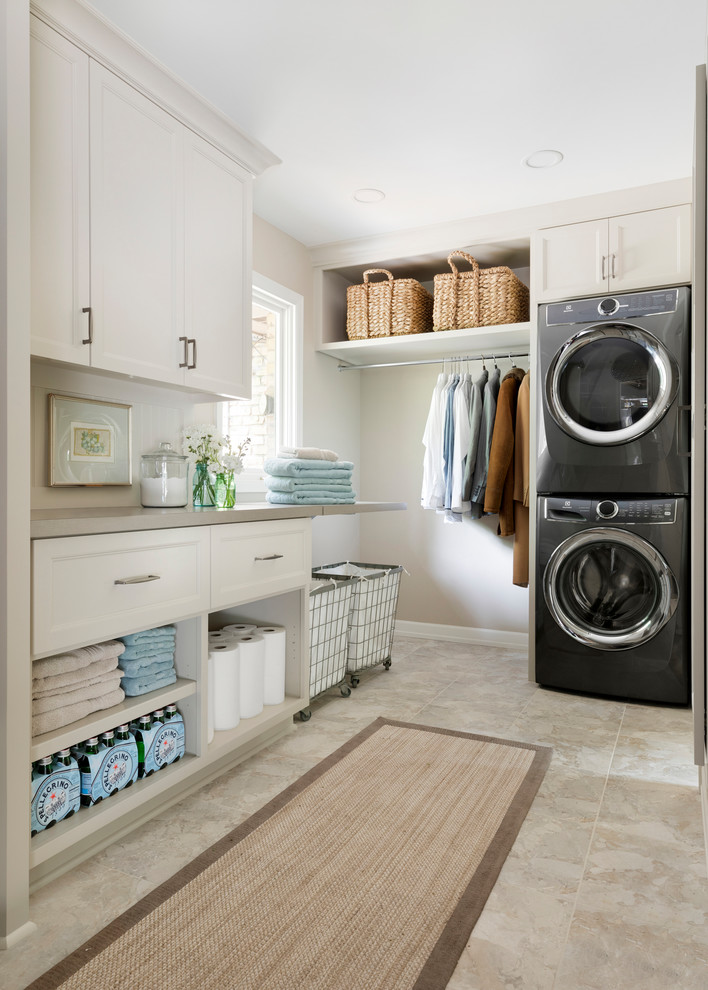 Design ideas for a mid-sized traditional galley laundry room in Minneapolis with flat-panel cabinets, beige cabinets, laminate benchtops, beige walls, vinyl floors, a stacked washer and dryer, multi-coloured floor and beige benchtop.