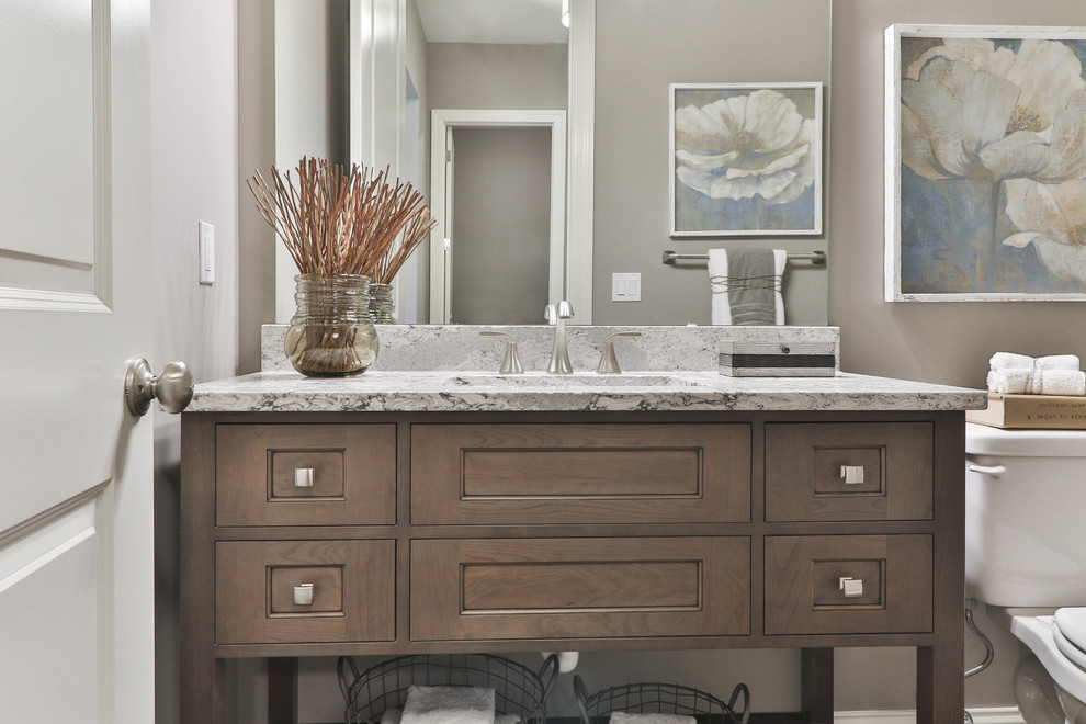 This is an example of a mid-sized transitional 3/4 bathroom in St Louis with shaker cabinets, dark wood cabinets, an alcove tub, a shower/bathtub combo, a two-piece toilet, white tile, porcelain tile, beige walls, vinyl floors, an undermount sink, granite benchtops, grey floor and a shower curtain.