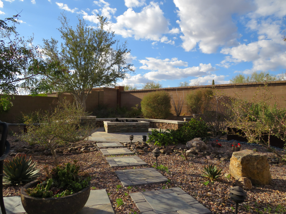 Immagine di un giardino xeriscape moderno esposto in pieno sole di medie dimensioni e dietro casa in primavera con un focolare, pavimentazioni in cemento e recinzione in pietra