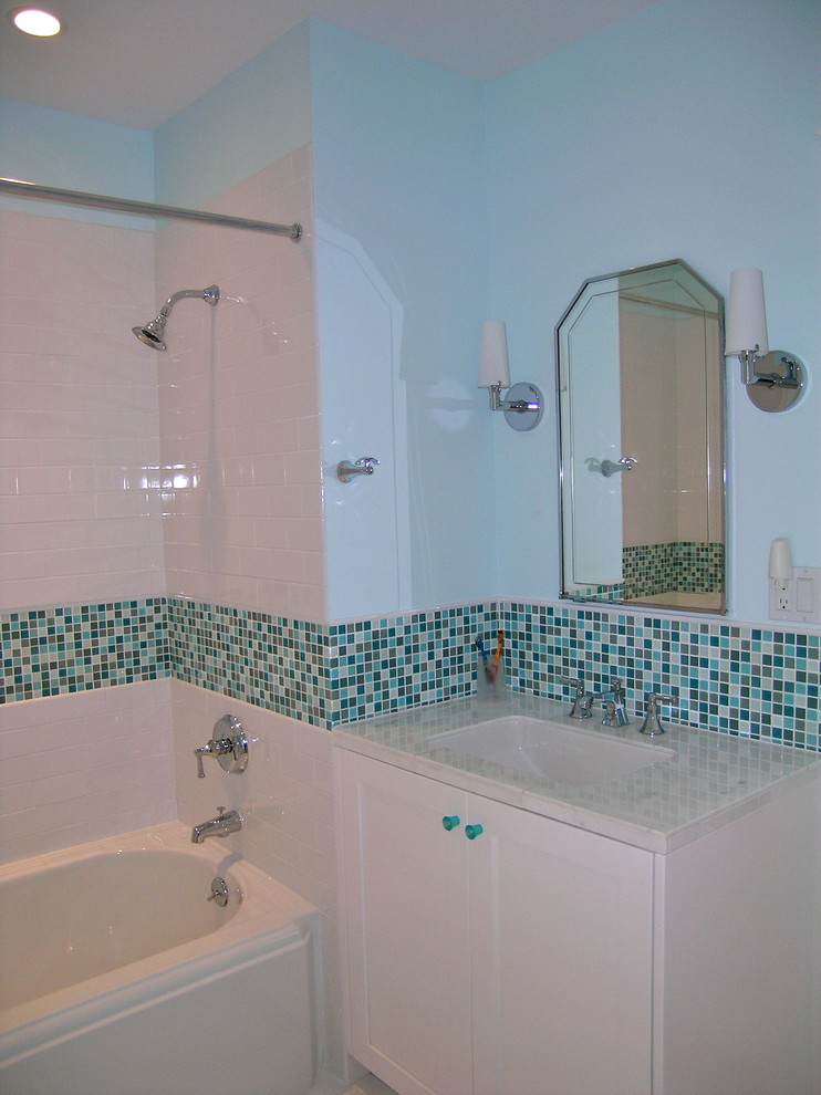 Klassisk inredning av ett badrum med dusch, med släta luckor, vita skåp, ett hörnbadkar, en hörndusch, blå kakel, glaskakel, blå väggar, ett nedsänkt handfat och granitbänkskiva