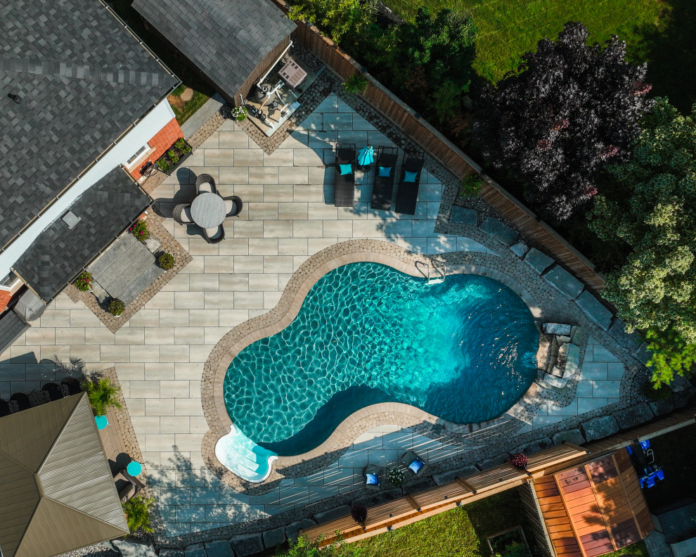 Design ideas for an expansive tropical backyard custom-shaped lap pool in Toronto with with a pool and concrete pavers.