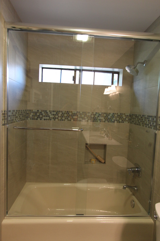 Photo of a small beach style kids bathroom in San Francisco with an undermount sink, recessed-panel cabinets, white cabinets, engineered quartz benchtops, an alcove tub, a shower/bathtub combo, a two-piece toilet, green tile, porcelain tile, blue walls and porcelain floors.